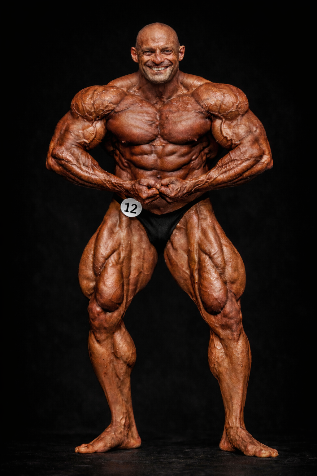 Aristos Aristeridou professional bodybuilder performing a front pose on stage, showcasing extreme muscle mass, definition, and conditioning
